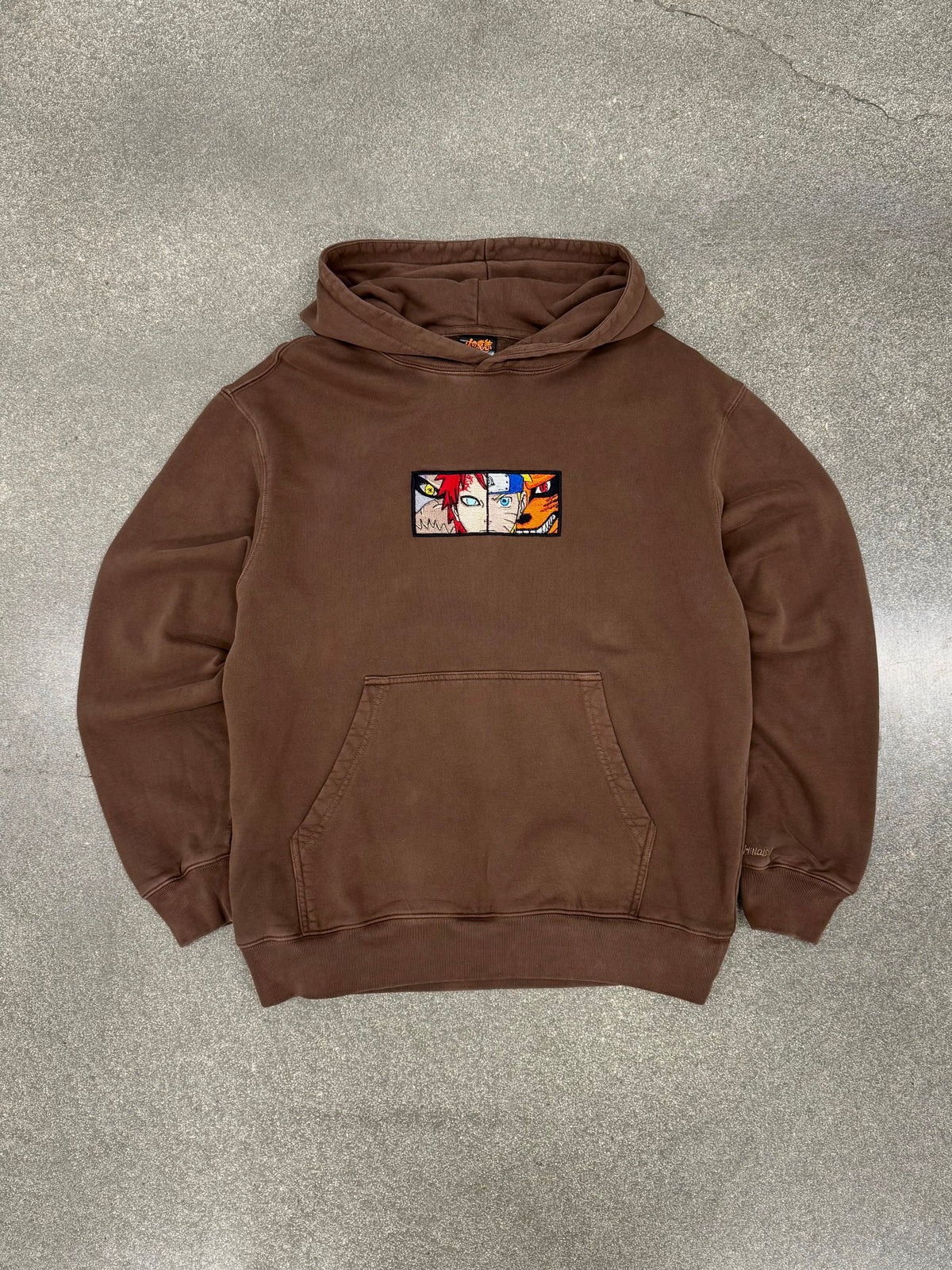Two Tails Fates brown hoodie laid flat, front view with embroidered Naruto and Gaara chest patch
