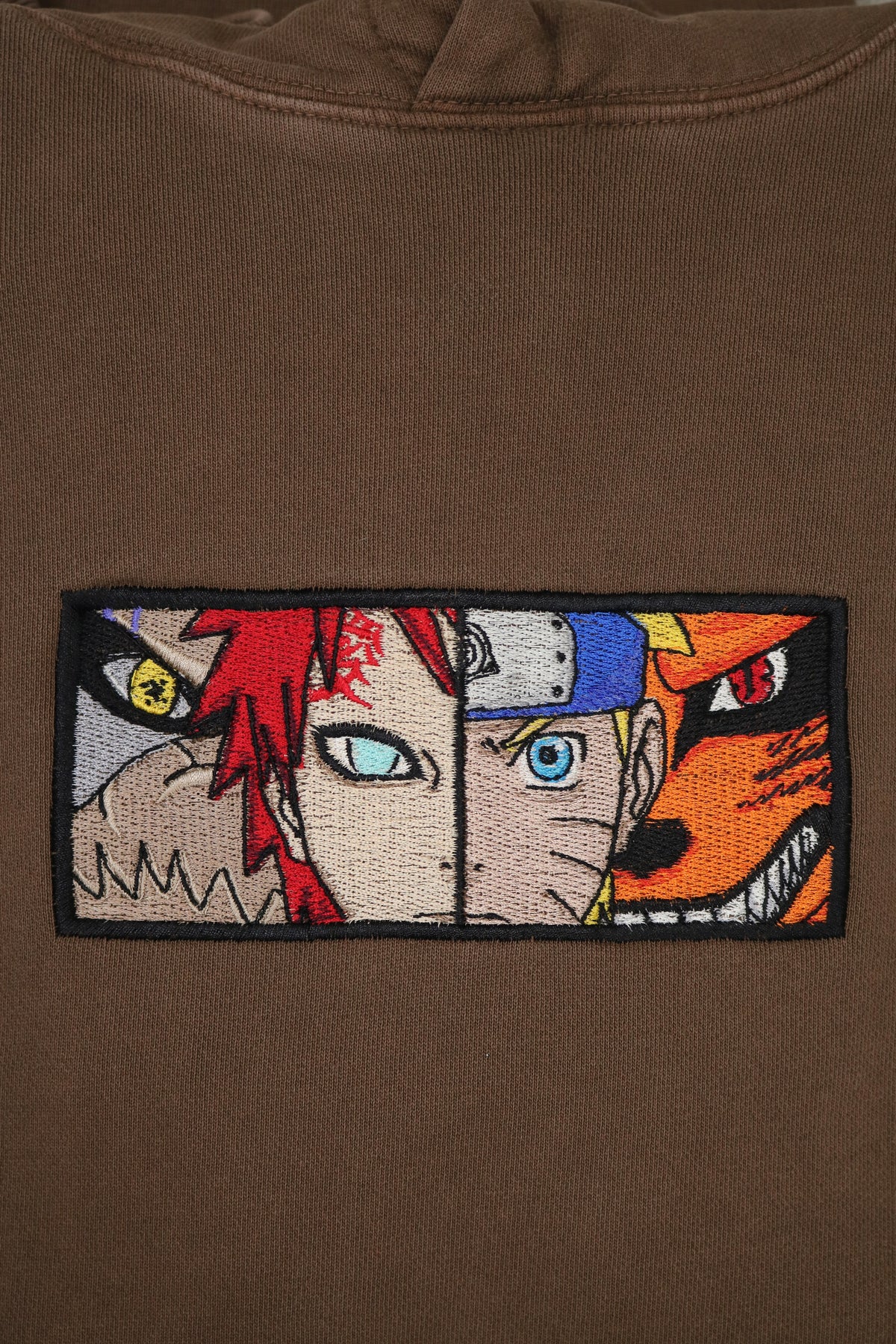 Close-up of chest embroidery: Gaara with Shukaku and Naruto with Kurama on a brown anime hoodie