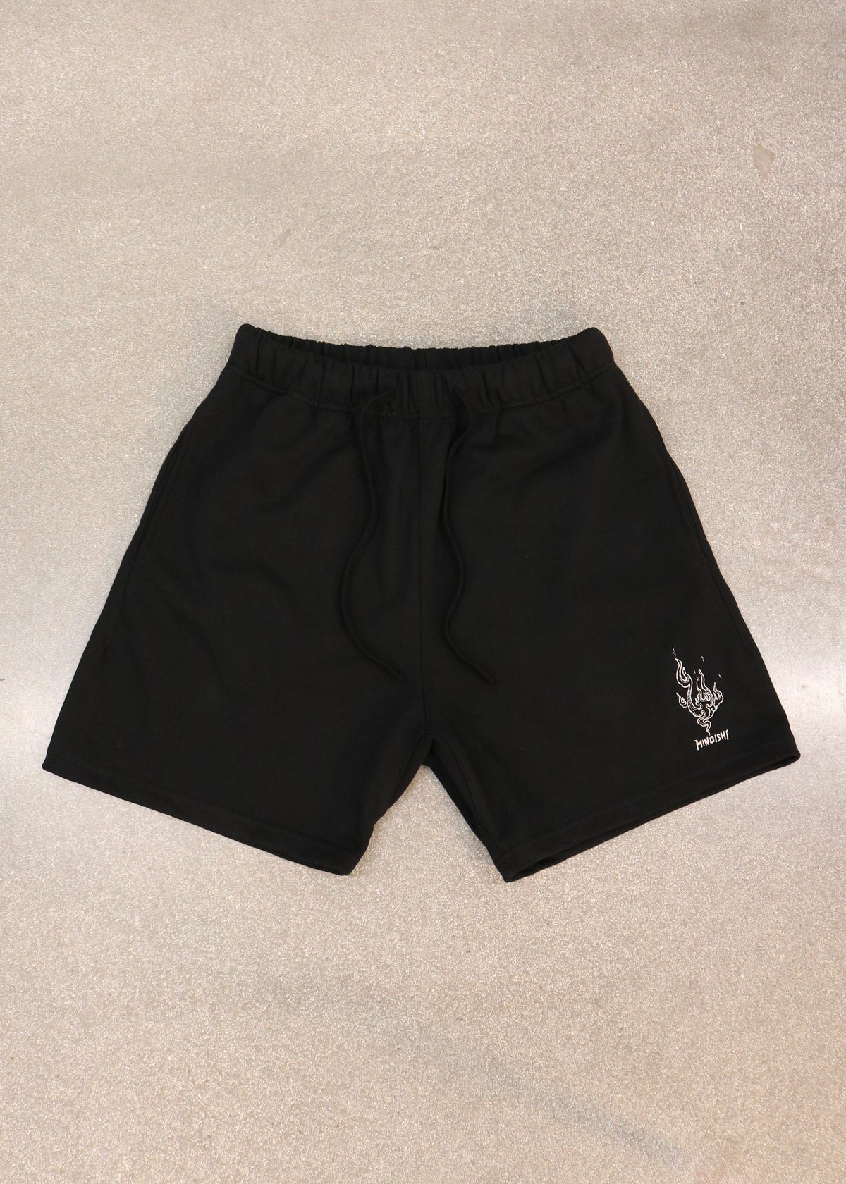 Will of Fire black shorts laid flat, front view with drawstring waist and embroidered flame on the leg