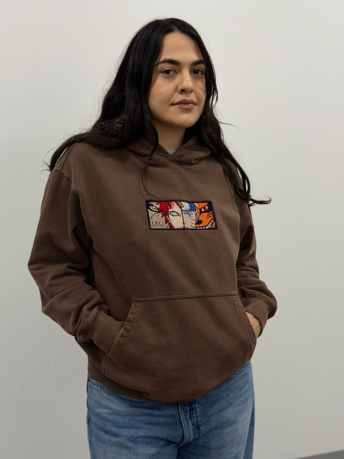 Model wearing the Two Tails Fates brown hoodie with embroidered Naruto and Gaara chest patch