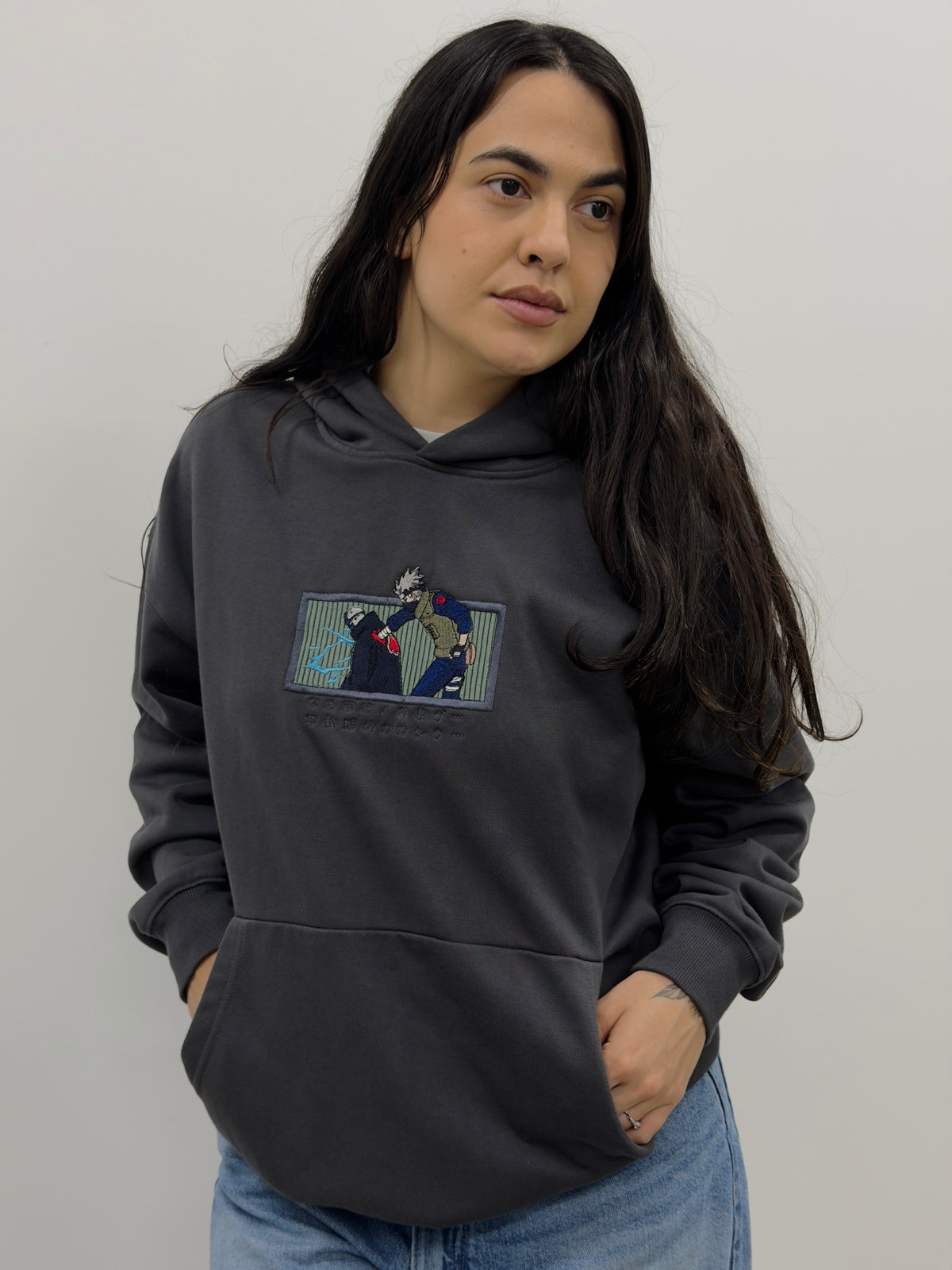 Model wearing the Copy Ninja Killshot dark gray hoodie with embroidered Kakashi vs Kakuzu chest patch