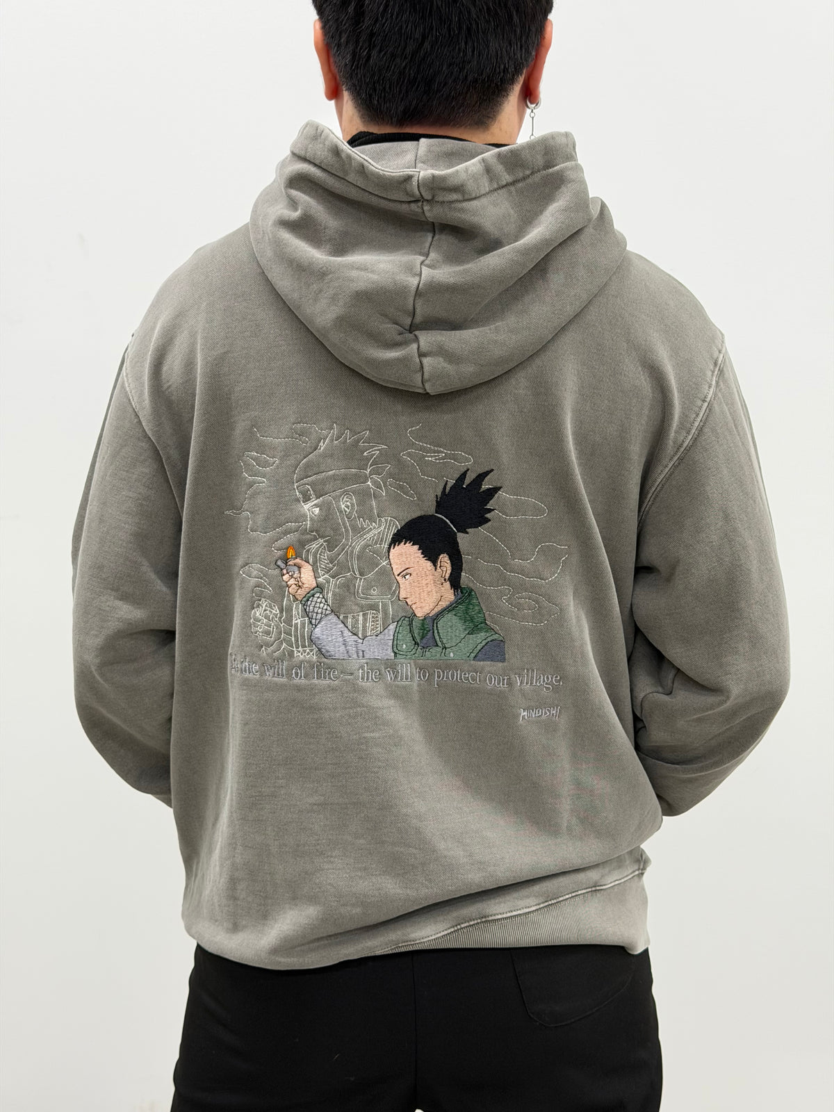 Model wearing the Legacy of the Flame gray hoodie, back embroidery of Shikamaru lighting Asuma's lighter