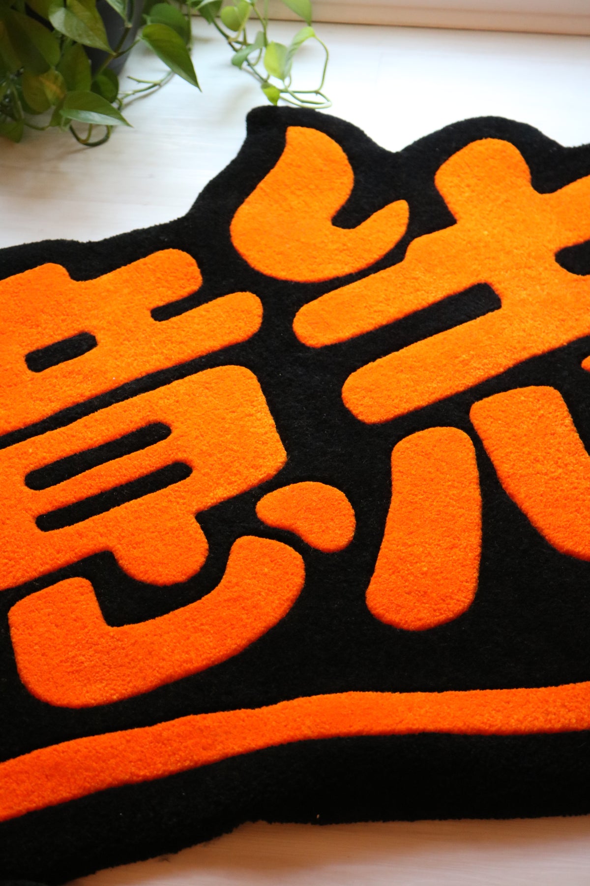 Close-up of the HINOISHI rug's plush orange kanji lettering, Will of Fire anime rug
