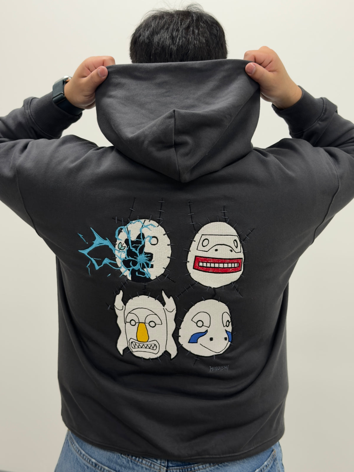 Model showing the back of the Copy Ninja Killshot hoodie with embroidered Kakuzu masks and Kakashi's lightning